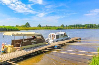 Lower Saxony Germany 06. July 2010 Beautiful natural landscape view panorama with forest trees jetty pier boats and water waves of Oste river in Hemmoor Hechthausen Cuxhaven Lower Saxony Germany.
