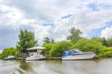 Lower Saxony Germany 06. July 2010 Beautiful natural landscape view panorama with forest trees jetty pier boats and water waves of Oste river in Hemmoor Hechthausen Cuxhaven Lower Saxony Germany.