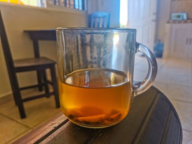 Glass or cup pot with hot ginger tea on a wooden table in Mexico.