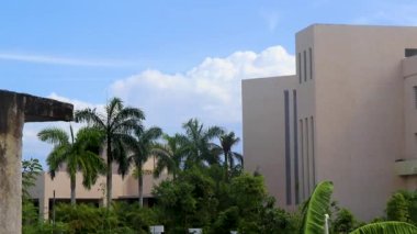 Tropical natural mexican palm trees and resort hotel building with cloudy blue sky background at Punta Esmeralda in Playa del Carmen Mexico.