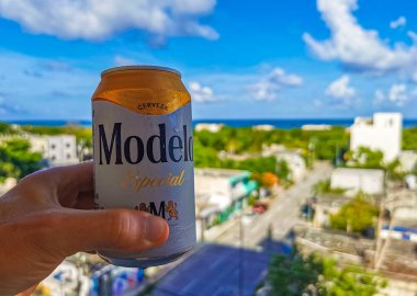 Playa del Carmen Meksika 04. Temmuz 2022 Modelo bira kutusu elinde inanılmaz şehir manzarası, Karayip okyanusu ve Quintana Roo Mexico 'daki Playa del Carmen plaj manzarası..