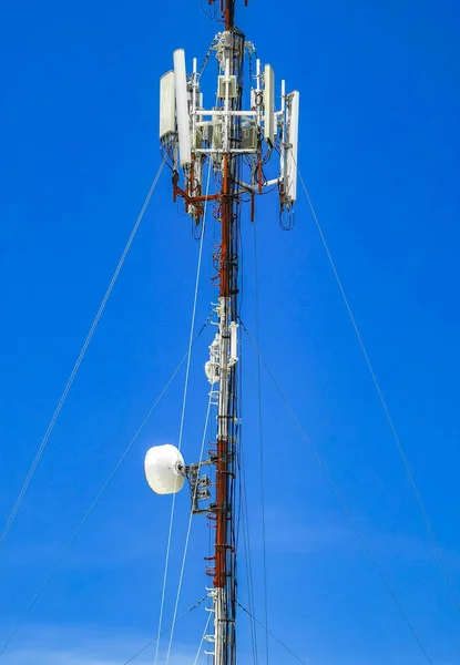 Red white 5G tower with blue sky background radiation kills us in Playa del Carmen in Mexico.