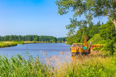 Beautiful natural landscape view panorama with forest trees jetty pier boats and water waves of Oste river in Hemmoor Hechthausen Cuxhaven Lower Saxony Germany.