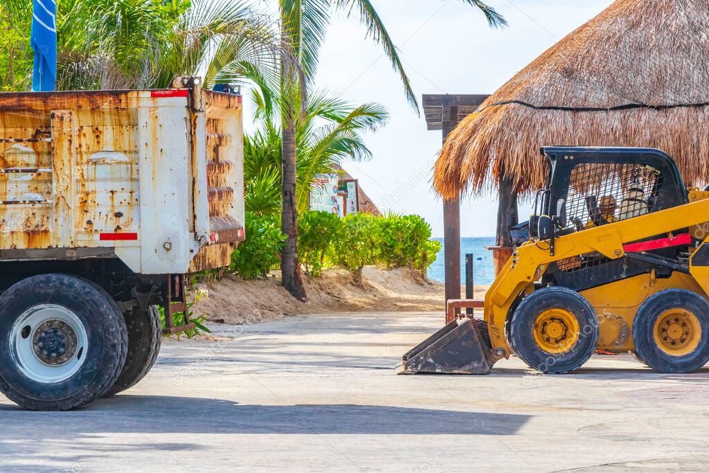 Dump truck and excavator remove sea grass seaweed sargazo from beach in Playa del Carmen Quintana Roo Mexico.