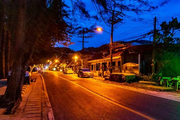 Landscape and cityscape panorama at night with street road cars building houses forest jungle nature and mountain in Naithon Beach on Phuket island Thailand in Southeast Asia.