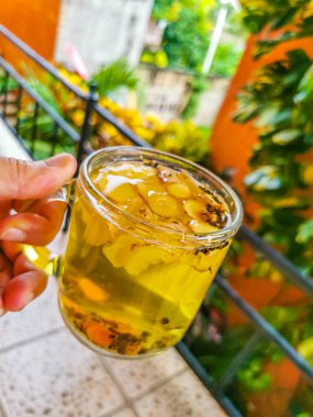 Glass or cup pot with hot ginger tea on a wooden table in Mexico.