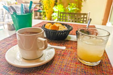 Playa del Carmen Quintana Roo Mexico 'daki PapaCharly Papa Charly restoranında bir fincan siyah americano kahveli ekmek suyu yemeği ve içecek..