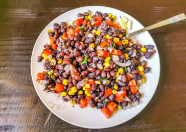 Vegetable dish soup with beans peas potatoes onions tomato and garlic on a white plate bowl with fork or spoon in Mexico.