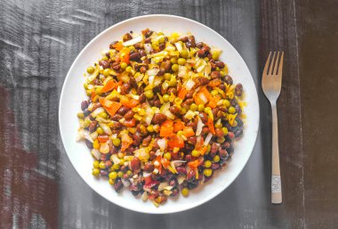 Vegetable dish soup with beans peas potatoes onions tomato and garlic on a white plate bowl with fork or spoon in Mexico.
