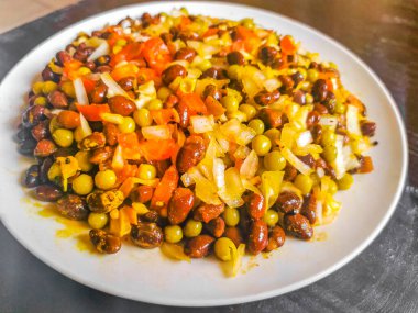 Vegetable dish soup with beans peas potatoes onions tomato and garlic on a white plate bowl with fork or spoon in Mexico.