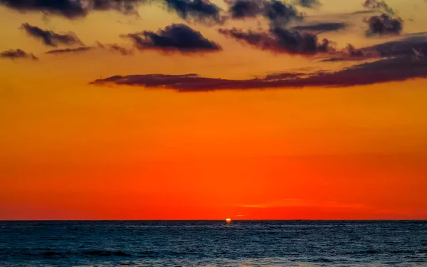 Beautiful stunning colorful and golden sunset in yellow orange red on beach and big wave panorama in tropical nature in Zicatela Puerto Escondido Oaxaca Mexico.