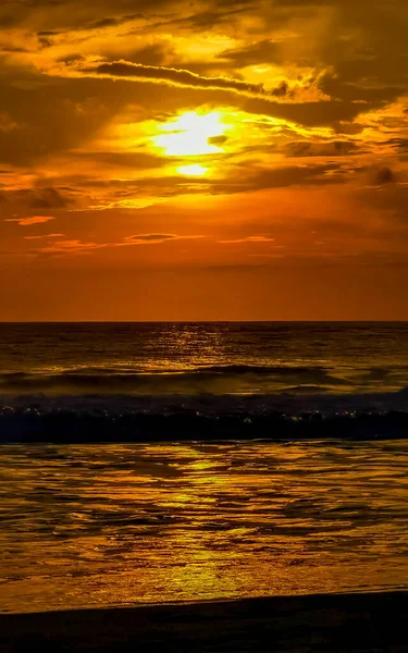 Beautiful stunning colorful and golden sunset in yellow orange red on beach and big wave panorama in tropical nature in Zicatela Puerto Escondido Oaxaca Mexico.