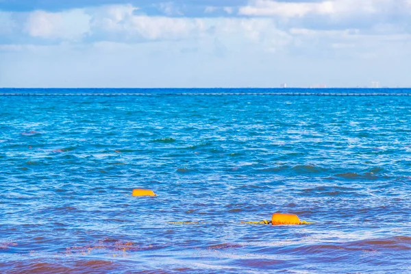 Beautiful blue and turquoise water waves ocean and yellow red orange buoy and ropes in the water of Playa del Carmen in Quintana Roo Mexico.