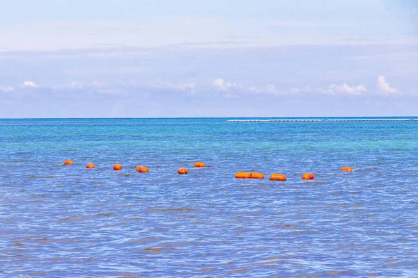 Beautiful blue and turquoise water waves ocean and yellow red orange buoy and ropes in the water of Playa del Carmen in Quintana Roo Mexico.