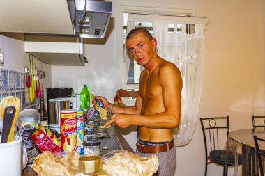 Genç adam Braunlage Goslar Aşağı Saksonya Almanya 'sında üstsüz yemek yapmaya çalışıyor..