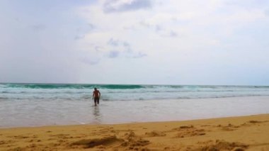 Erkek turist, Thalang Phuket Tayland 'daki turkuaz berrak suyla Nai Thon Naithon Sahili koyunda koşuyor ve yüzüyor.