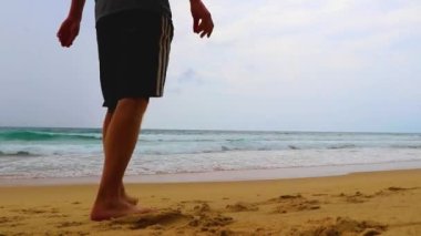 Erkek turist, Thalang Phuket Tayland 'daki turkuaz berrak suyla Nai Thon Naithon Sahili koyunda koşuyor ve yüzüyor.