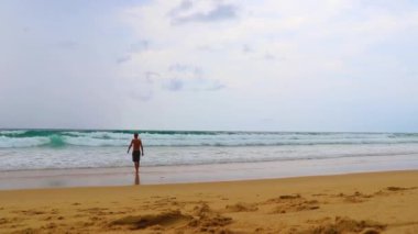 Erkek turist, Thalang Phuket Tayland 'daki turkuaz berrak suyla Nai Thon Naithon Sahili koyunda koşuyor ve yüzüyor.