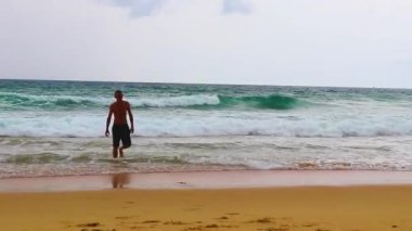 Erkek turist, Thalang Phuket Tayland 'daki turkuaz berrak suyla Nai Thon Naithon Sahili koyunda koşuyor ve yüzüyor.