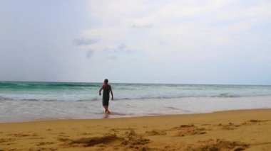 Erkek turist, Thalang Phuket Tayland 'daki turkuaz berrak suyla Nai Thon Naithon Sahili koyunda koşuyor ve yüzüyor.