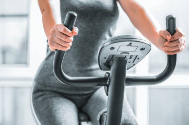 Kız egzersiz bisikletine biniyor, spor yapma, aşırı kilo yakma, rehabilitasyon ya da sakatlıktan sonra iyileşme konsepti..