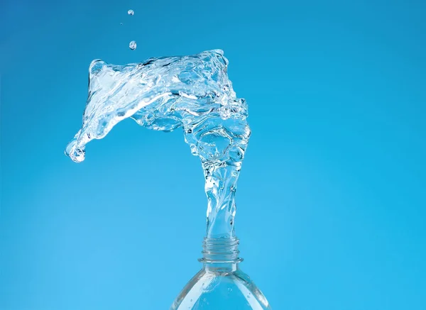 青い背景にPetボトルから脱出する滴と水のスプラッシュ 純水の概念 — ストック写真