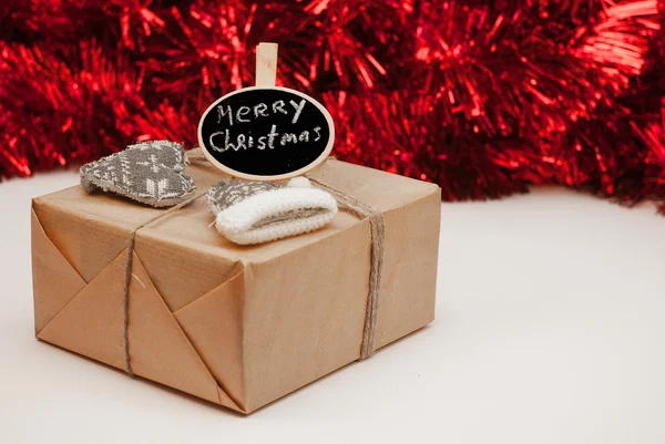 Wrapped Christmass gift box with sign on red sparkling backgrou — Stock Photo, Image