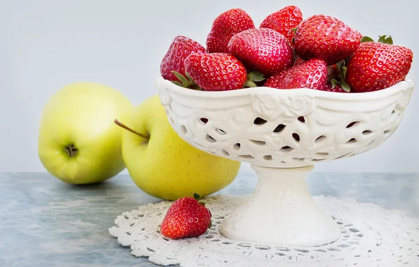 Pommes et fraises dans un vase sur fond de marbre . — Photo