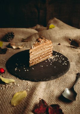 Görüntü - kırsal ve karanlık sonbahar arka planında Medovik kekinin (tatlılar) bir parçası. Doğum günü kutlaması için fındıklı büyük Medovik kekinin (tatlı) yemek fotoğrafçılığı.