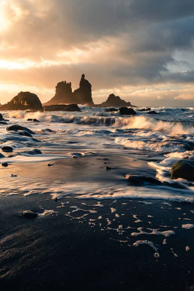 Kuzey Tenerife sahilinde gün batımında kumlu ve taşlı güzel bir sahil manzarası. Kanarya Adaları 'nda altın güneşli Atlantik dalgalı okyanus. Playa de Benijo 'nun İspanya' daki koyu renkli fotoğrafı.