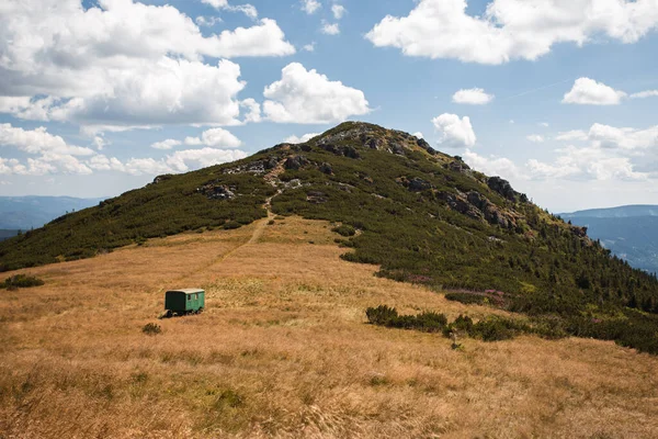 Ridge of the mountain and dry meadow with green caravan under the hill. Landscape photo of hill in national park in Slovakia Europe on sunny day.