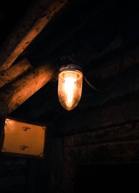 Tavandan sarkan klasik (retro) ampulün dikey koyu fotoğrafı. Geceleri rahat ampul - yaşam tarzı fotoğrafçılık.