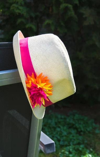 Summer hat hanging on garden chair — Stock Photo, Image