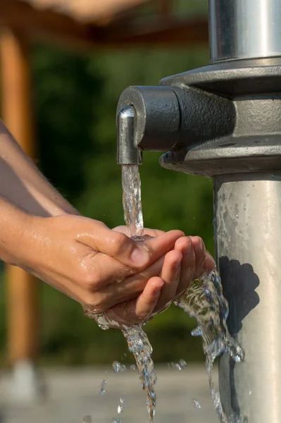 Frisches und kühles Wasser aus einer Quelle mit den Händen auffangen — Stockfoto