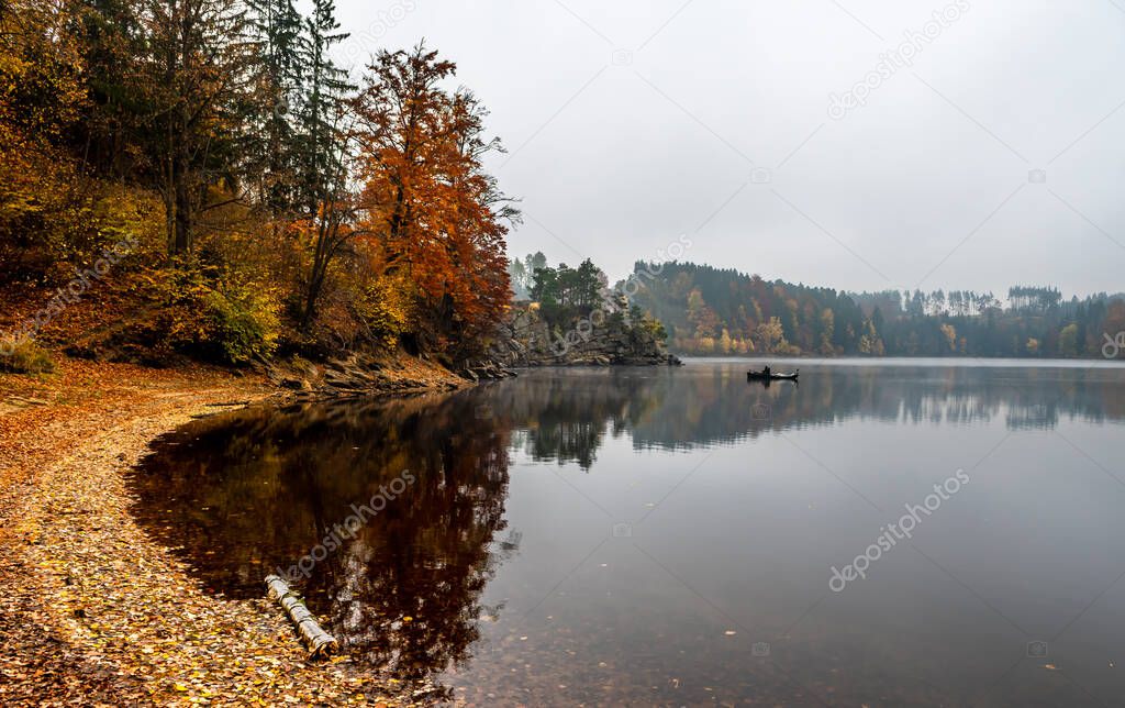 Foggy Landscape With Fishermans Boat On Calm Lake And Autumnal Forest At Lake Ottenstein In Austria