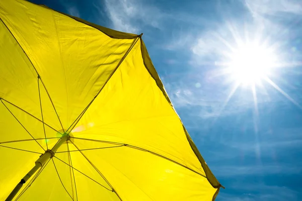 Parlak güneş ve mavi gökyüzü ile sarı şemsiye