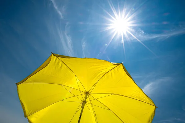 明亮的太阳和蓝天的黄色雨伞 — 图库照片