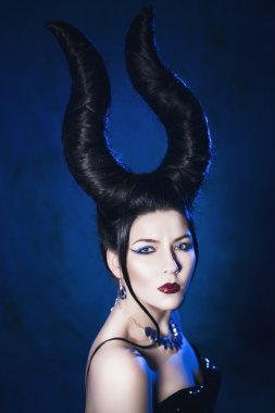 bir peri masalı bir saçlı güzel kadının boynuzları ve takı mavi aydınlatmalı kameraya bakarak bir spot ışığı