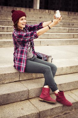 esmer kadın basamaklarında oturan ve retro kamera sokak selfie alarak hipster kıyafeti. tonlu görüntü