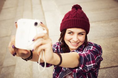 esmer kadın basamaklarında oturan ve retro kamera sokak selfie alarak hipster kıyafeti. tonlu görüntü