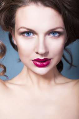 yaratıcı makyaj menekşe göz gölgeler tam kırmızı dudaklar, güzel esmer kadın mavi gözleri ve kıvırcık saçlı eliyle yüzünde
