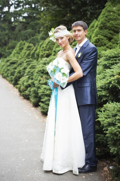 Jeune couple embrassant en robe de mariée. Mariée tenant bouquet avec des lis blancs — Photo