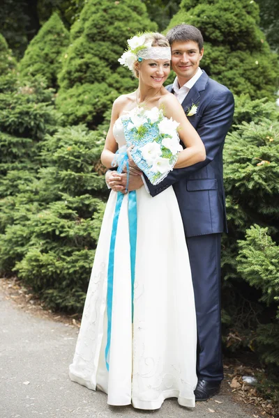 Jeune couple embrassant en robe de mariée. Mariée tenant bouquet avec des lis blancs — Photo