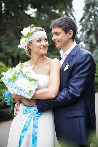 Pareja joven besándose en vestido de novia. Ramo de novia con lirios blancos — Foto de Stock