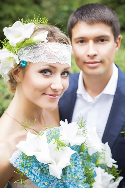 Молода пара цілується у весільній сукні. Наречена тримає букет з білими ліліями — стокове фото