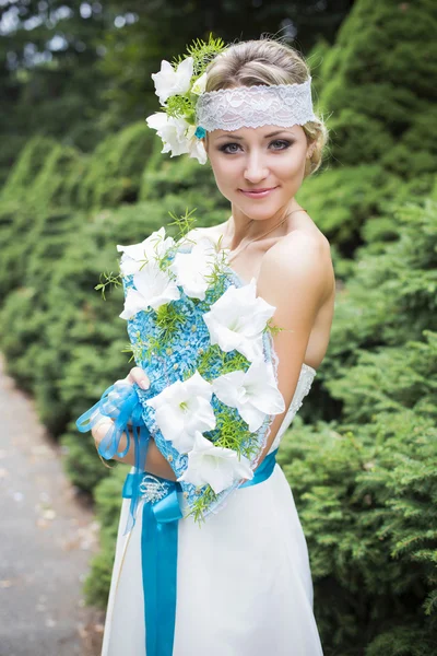Blond kobieta w sukni ślubnej, trzymając bukiet z białych lilii — Zdjęcie stockowe
