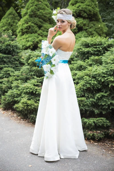 Блондинка в свадебном платье держит букет с белыми лилиями — стоковое фото