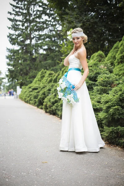 Femme blonde en robe de mariée tenant bouquet avec des lis blancs — Photo