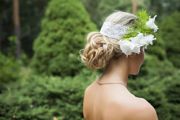 Femme blonde en robe de mariée tenant bouquet avec des lis blancs — Photo