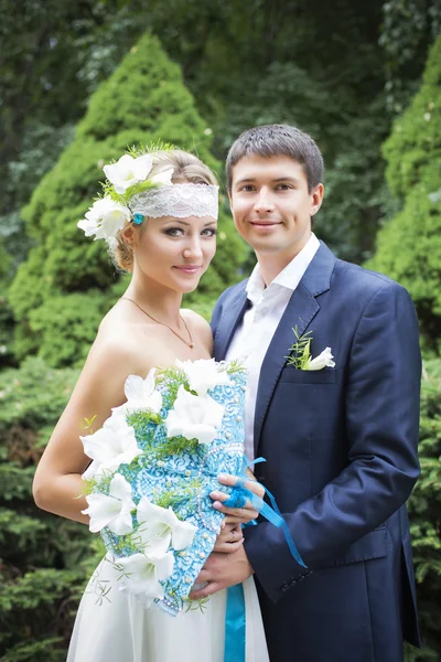 Jeune couple embrassant en robe de mariée. Mariée tenant bouquet avec des lis blancs — Photo